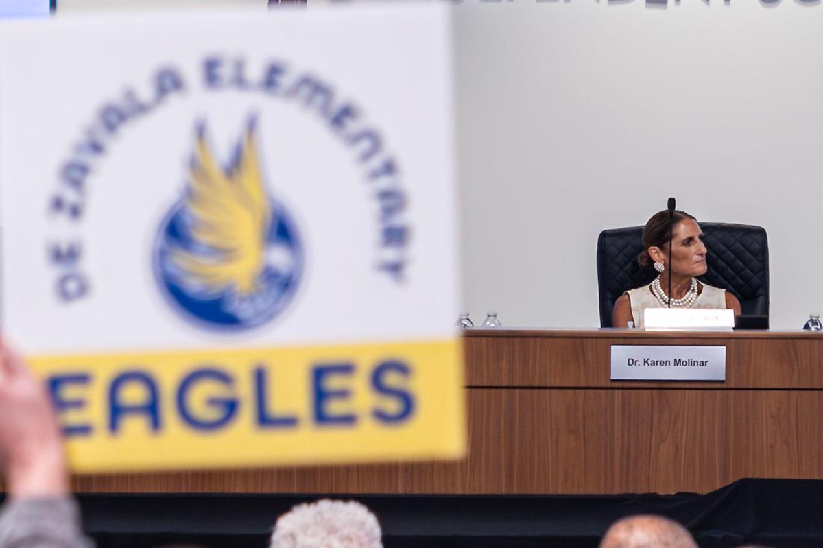 Karen Molinar, the Superintendent of Fort Worth Independent School District, listens to public comment as meeting attendees hold signs in support of keeping De Zavala Elementary open during a FWISD School Board Meeting at the District Administration Building in Fort Worth on Tuesday, May, 20, 2025.
