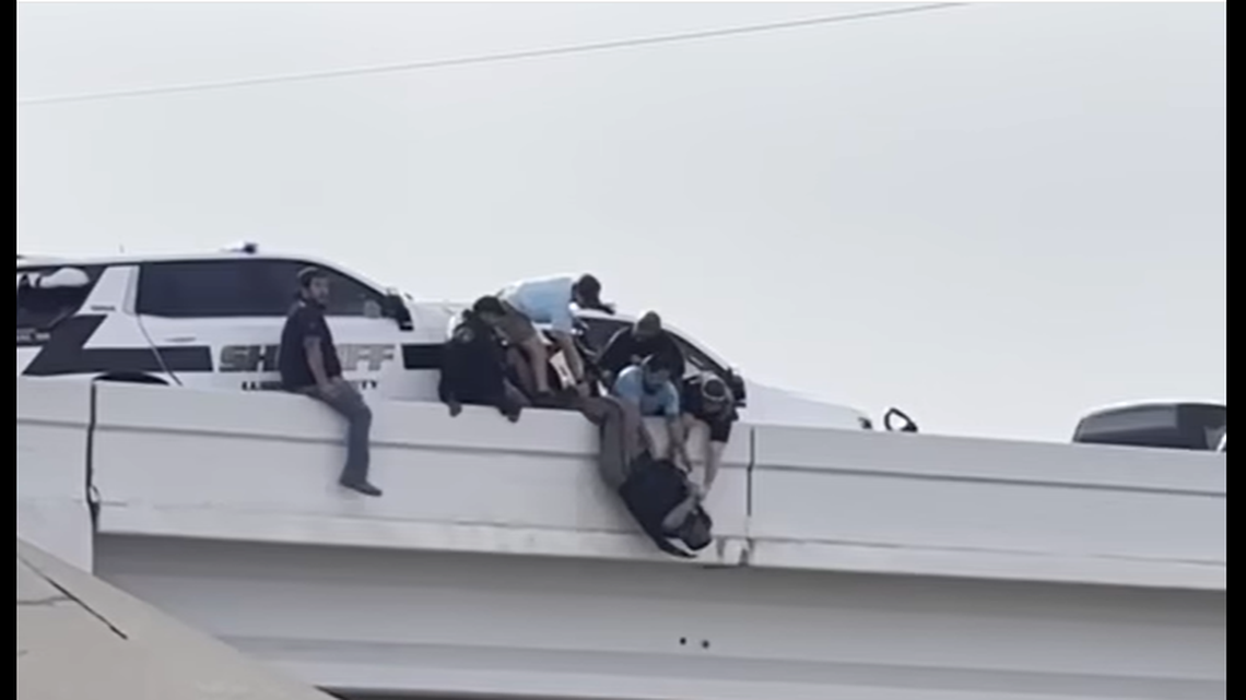 A deputy nearly fell from an overpass after a crash in Texas, but bystanders stepped in to help, officials say.
