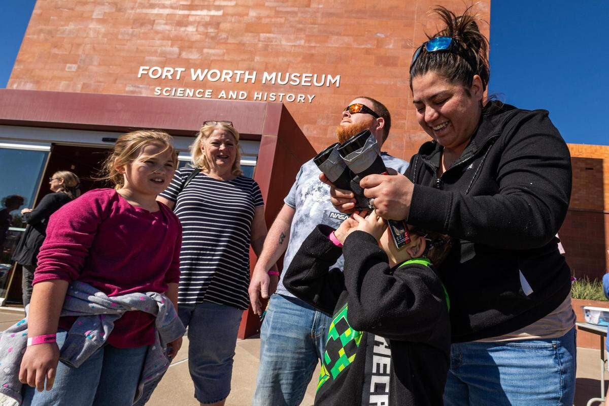 Scotland Roberts, 7, uses solar binoculars with the help of his mother Jessica Roberts during the Annular Solar Eclipse event at the Fort Worth Museum of Science & History on Saturday, Oct. 14, 2023.