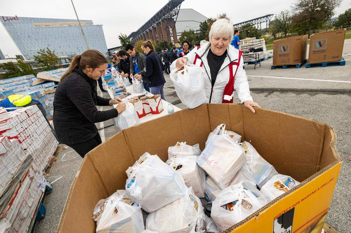 Gilli Kalb, left, and Lori Balogh put bags full of various Thanksgiving side dishes into a pile for distribution during the 4th annual Thanksgiving Mobile food distribution at AT&T Stadium in Arlington on Friday, November 17, 2023.