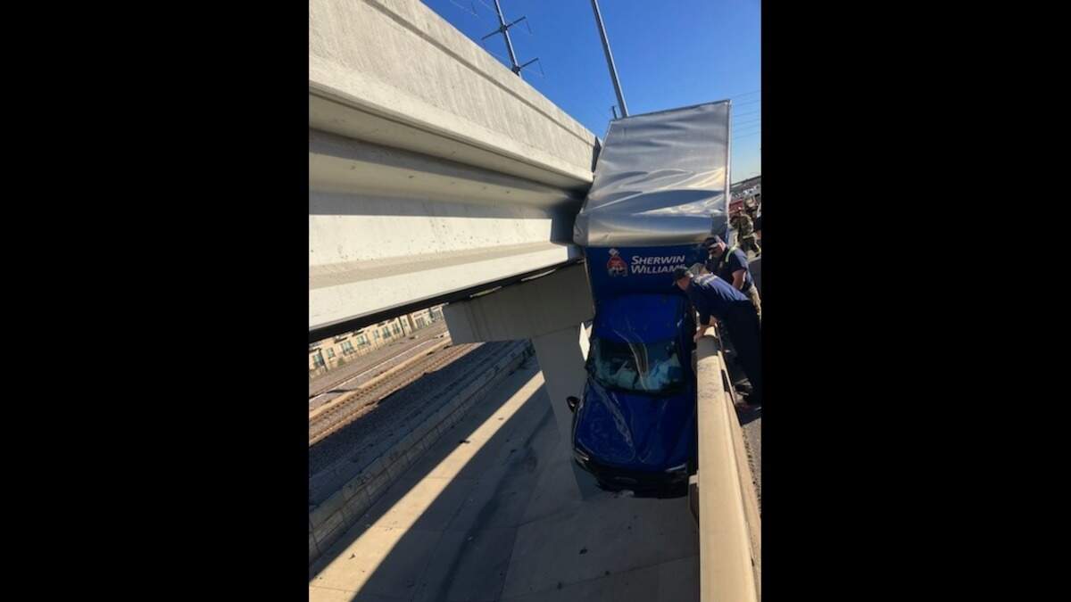 First responders including Dallas Fire-Rescue and Dallas County Sheriff’s Office traffic deputies work to rescue a driver in a Sherwin-Williams truck hanging off a bridge on northbound Interstate 35 at Victory Avenue on Monday afternoon.