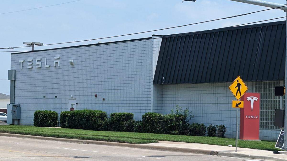 A nondescript white brick building with "TESLA" written on the side.