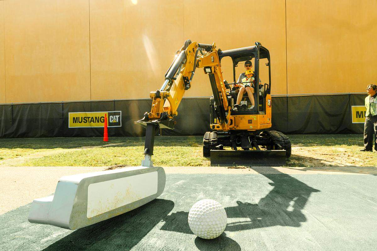 Attraction attendees playing golf with the Exca-Putter, a Cat 301.5 mini excavator to play golf area at Putts and Bolts Attraction.