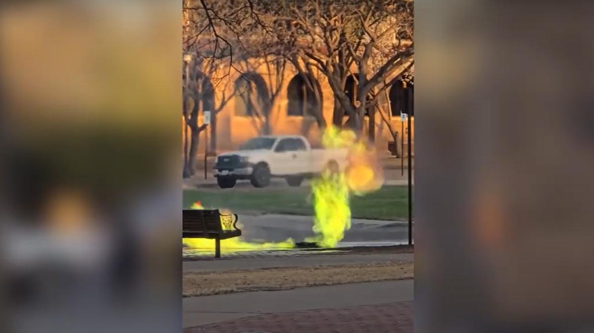 Green flames shoot out from underneath a manhole on the campus of Texas Tech University in Lubbock on Wednesday evening.