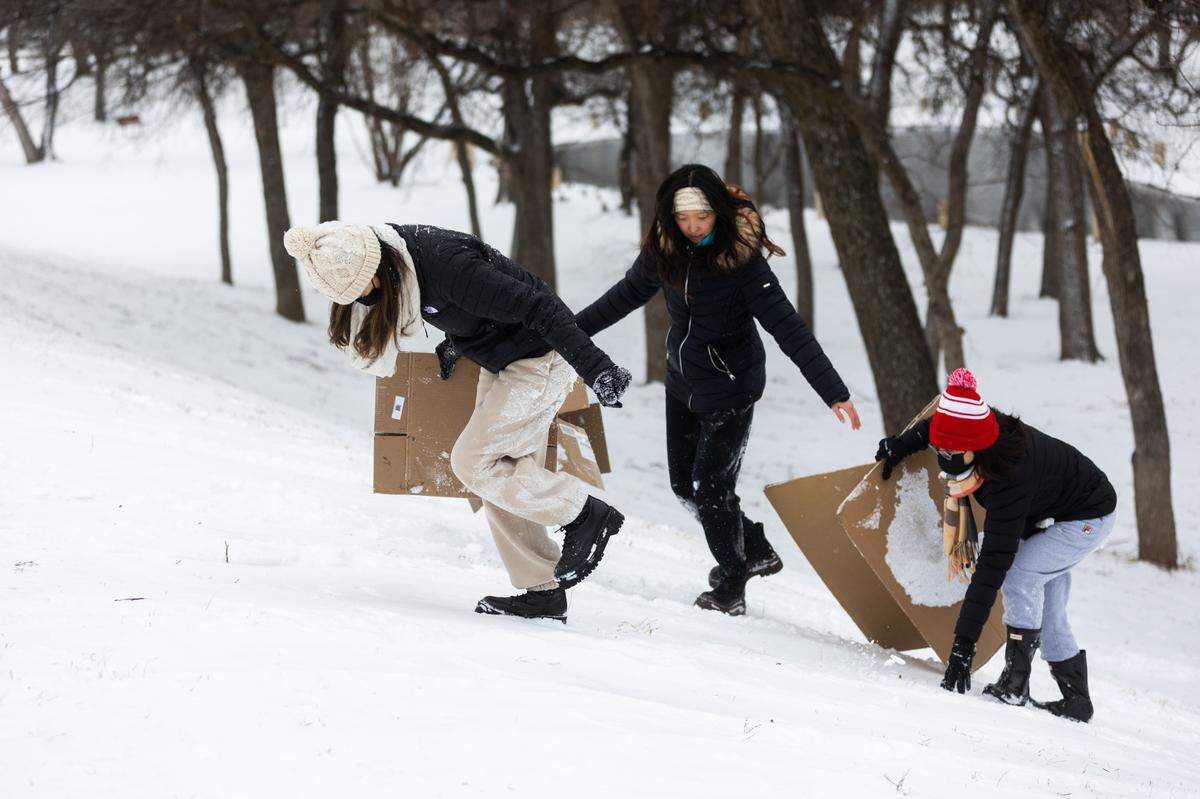 Quynh Tran, Hannah Lee and Jessica Ngyen climb up the hill to sled in the snow Thursday, Feb. 3, 2022, in Fort Worth.