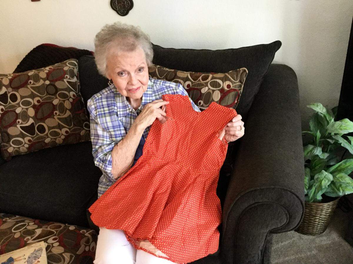 Dean McLaughlin holds up a dress her daughter, Dana, hand-sewed at age five.