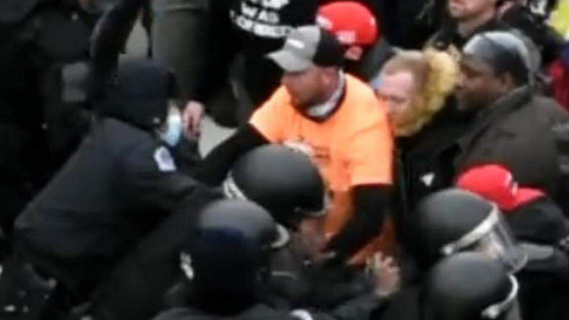 Dustin Ray Williams (in orange) pushed and shoved police and grabbed the arm of an officer during the Jan. 6 riot at the U.S. Capitol, according to an FBI complaint.