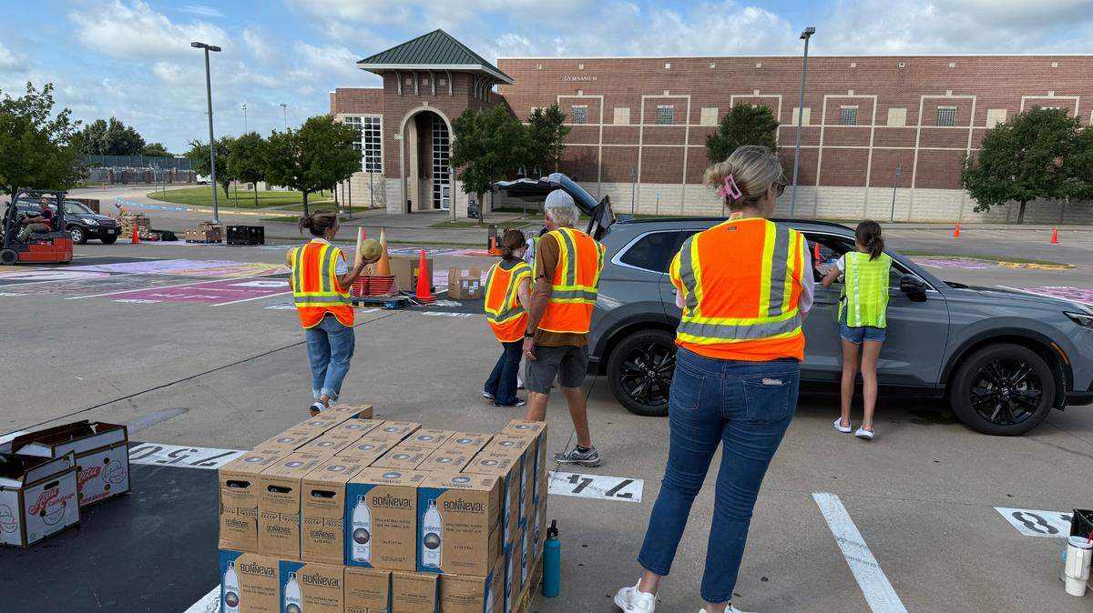 Volunteers load a trunk with a case of water and fresh produce during the Tarrant Area Food bank distribution in Weatherford.