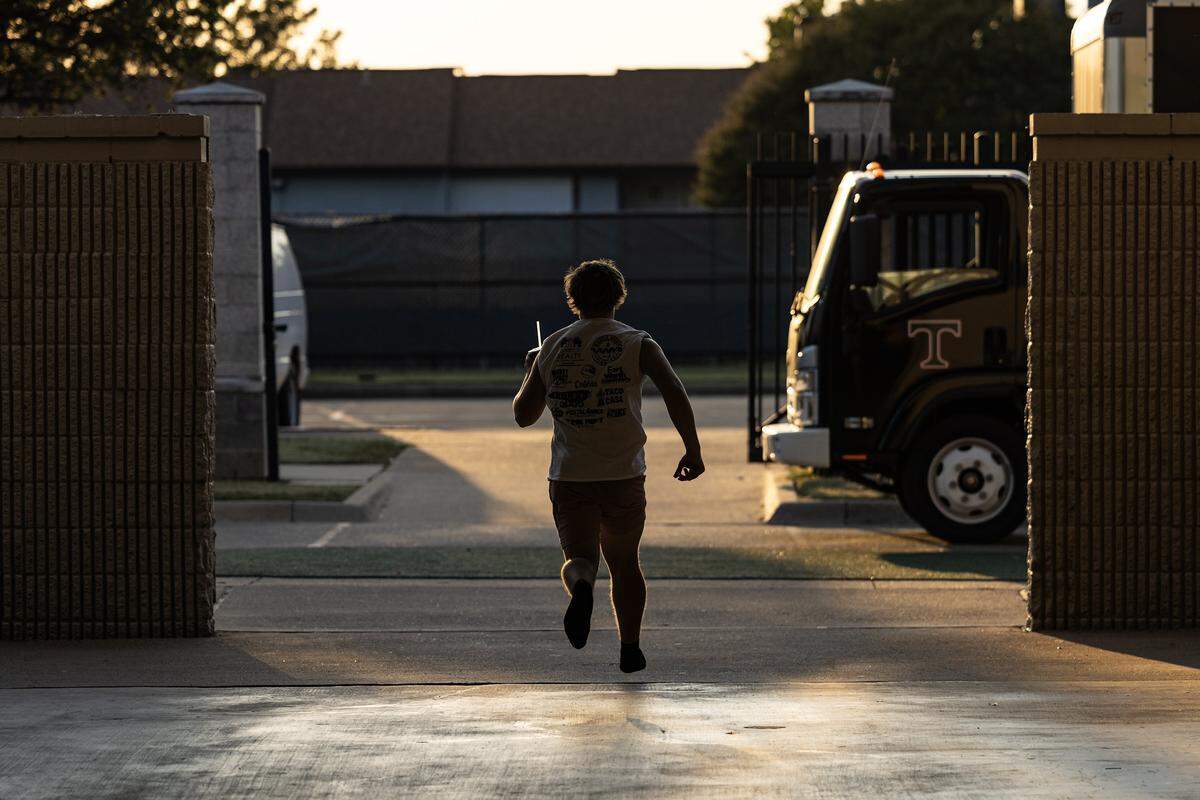 A person can be seen from behind as they run through a parking lot.