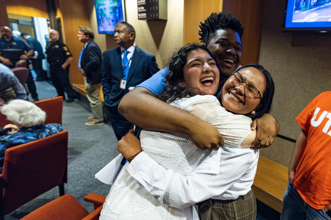 Emman Khan, Trevor Mccullough, and Vianka Gutierez, members of the University of Texas Arlington student government celebrate together after the Tarrant County Commissioners vote 4-1 to keep all 50 voting locations and adding an additional one at the end of a special meeting at the Tarrant County Commissioners Court in the Tarrant County Administration Building in Fort Worth on Thursday, Sept. 12, 2024. UTA is one of the voting locations chosen to remain as an election voting center.