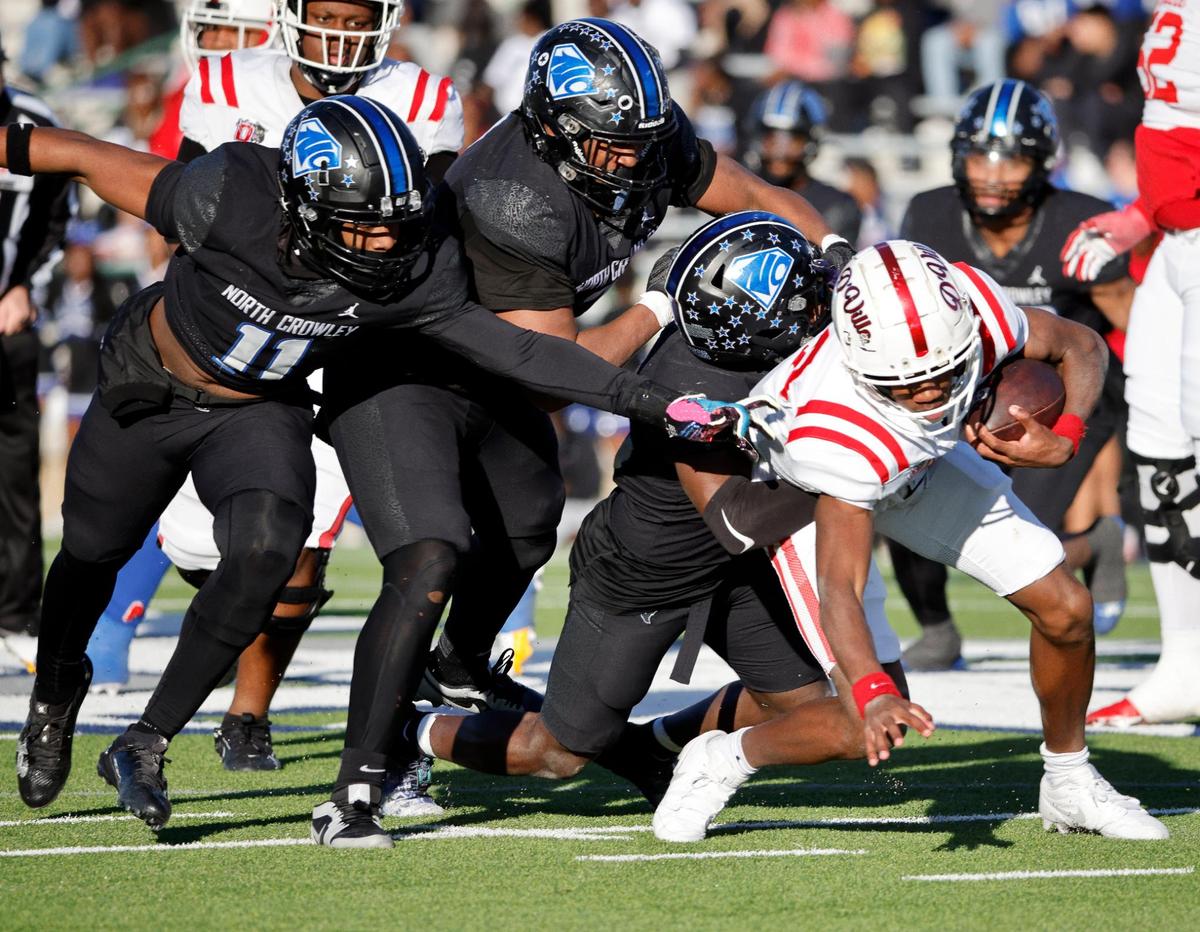 Duncanville quarterback Keelon Russell (12) is dropped for a loss by the North Crowley defense including defensive lineman Dacorien Thompson (7) and linebacker Jabrelle Asberry (11) during the first half of a UIL Conference 6A Division I state semifinal football playoff game at Mesquite Memorial Stadium in Mesquite, Texas, Saturday, Dec. 09, 2023. Duncanville led North Crowley 24-0 at the half.