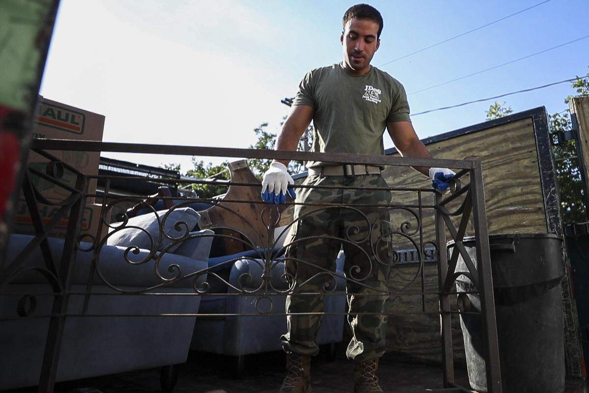 Alexander Matos gets a headboard ready to unload from the truck into the warehouse Wednesday, Aug. 7, 2019, at JDog Junk Removal and Hauling.