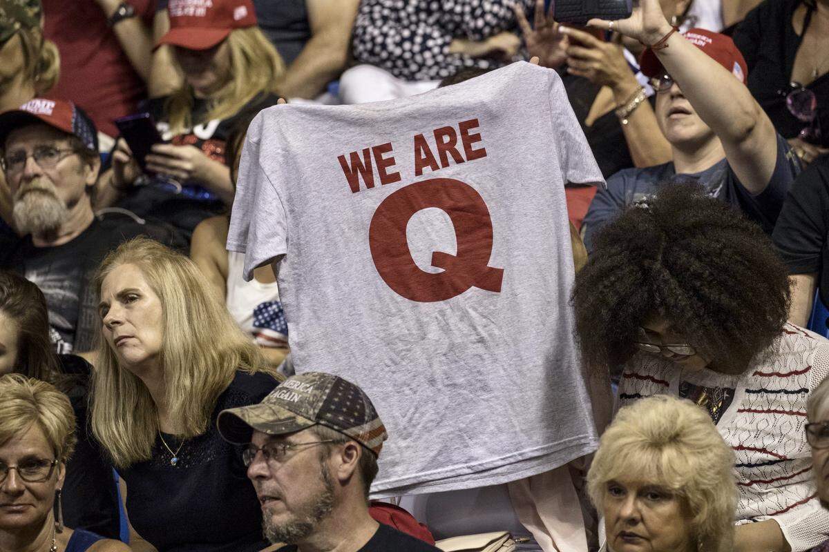 An attendee raises up a T-shirt with the words “We Are Q” before the start of a rally with U.S. President Donald Trump in Wilkes-Barre, Pa., on Aug. 2, 2018. Bloomberg photo by Victor J. Blue