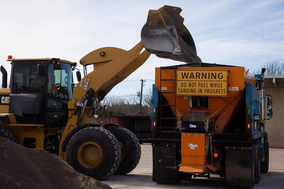 A tractor drops sand onto a truck in a demonstration as the city prepares for a winter storm Monday, Jan. 31, 2022, in Fort Worth.
