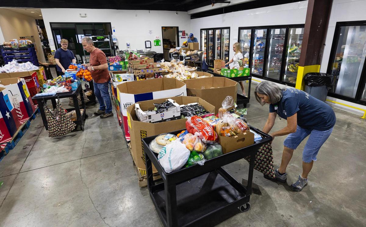 Volunteers at Community Link load carts full of groceries from their food pantry for pickup on Tuesday, July 22, 2025, in Saginaw.