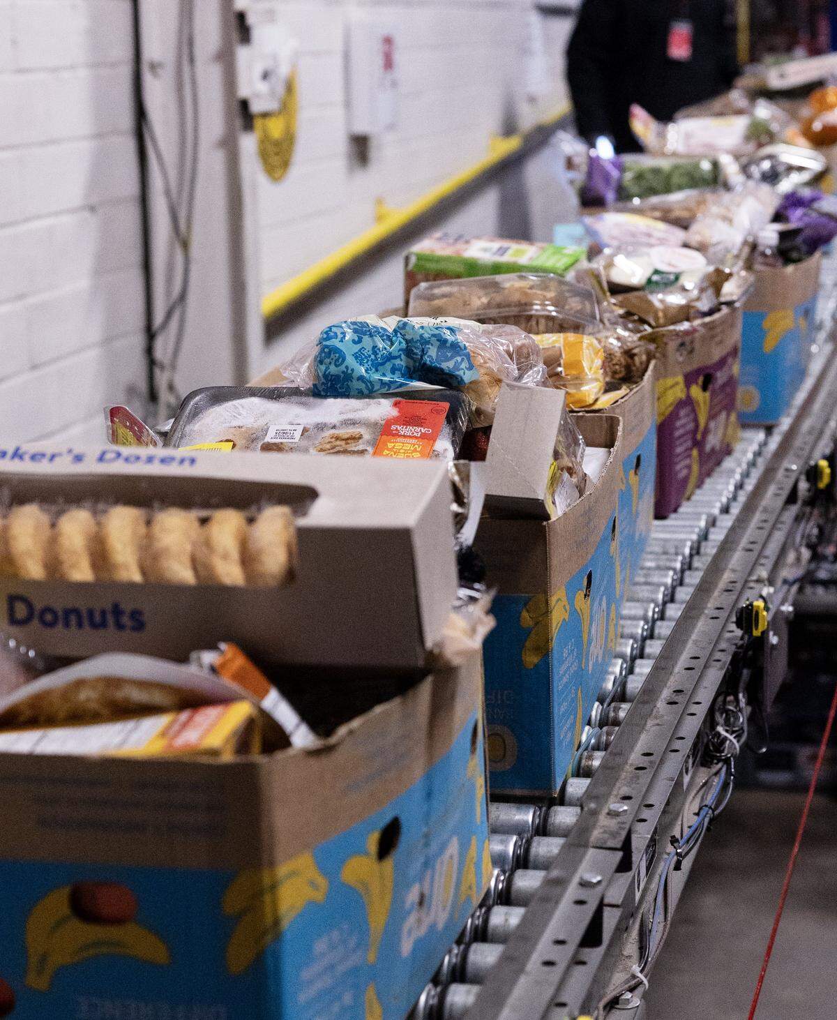Boxes of food roll on a conveyor belt to be distributed to those in need.