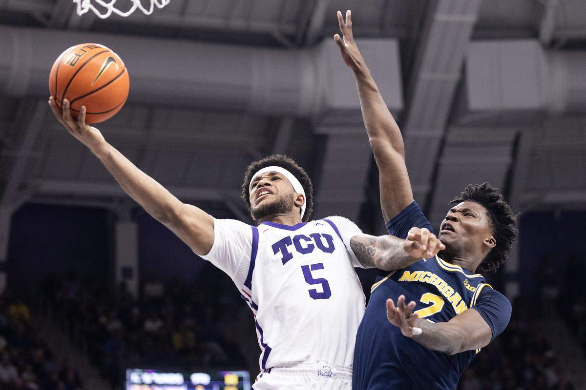 TCU guard Micah Robinson (5) goes up for a layup around Michigan guard L.J. Cason (2) in the first half of a NCAA basketball game between the TCU Horned Frogs and the Michigan Wolverines at Schollmaier Arena in Fort Worth on Friday, Nov.14, 2025.