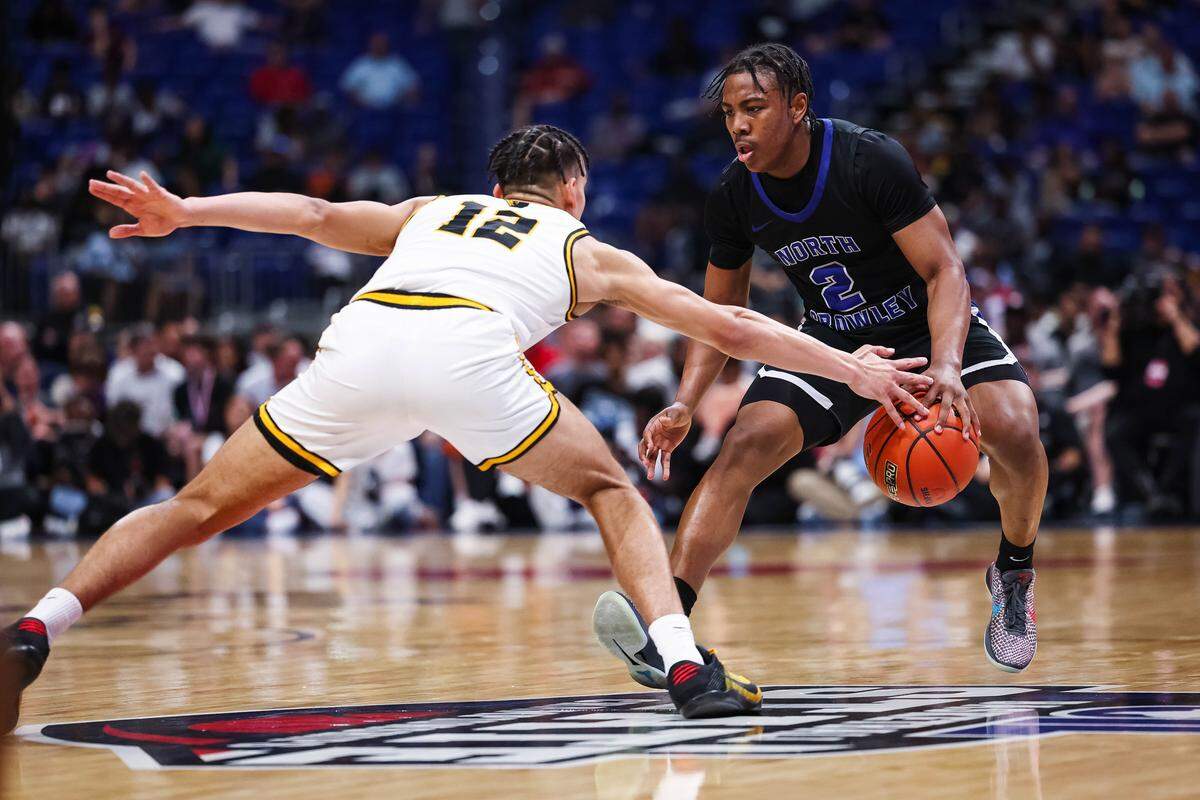 North Crowley guard Kameron Price (2) dribbles toward a San Antonio Brennan defender who reaches his arm out to deflect the ball in the Class 6A Division I state championship at The Alamodome in San Antonio, Texas, March 14, 2026.