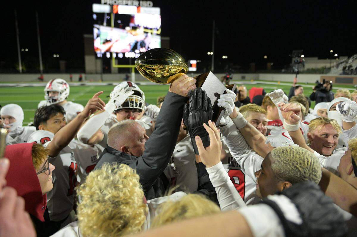 Argyle head coach Todd Rodgers lifts the Class 5A Division ll Region l trophy with his team after a winning the 5A Division II Region I playoff game against Lovejoy High School at Prosper ISD Children’s Health Stadium in Prosper, Texas on Friday, Dec. 6, 2024.