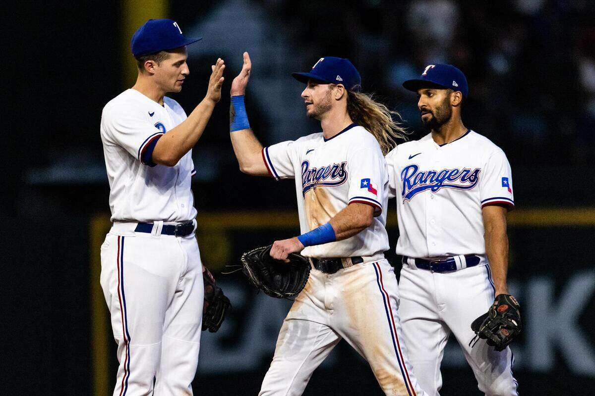 Texas Rangers teammates Corey Seager (5), Travis Jankowski (16) and Marcus Semien (2) give each other high-fives after defeating the Tampa Bay Rays 5-1 at Globe Life Field in Arlington, Texas on Wednesday, July 19, 2023.