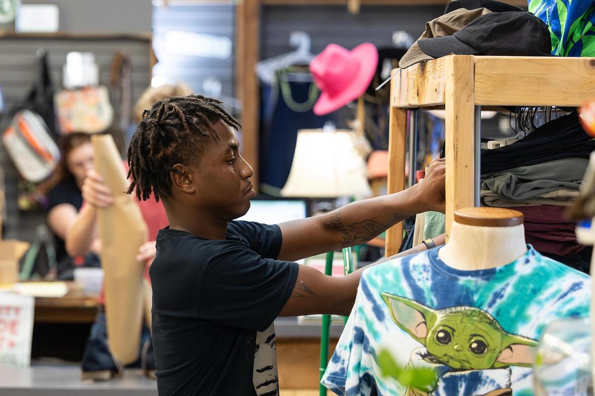 Volunteer Julian Taylor arranges clothes for sale at The Awareness Project store and café in Hurst on in June. The nonprofit aimed at reducing hunger, poverty and homelessness, is scheduled to close later this summer due to rising rent costs.