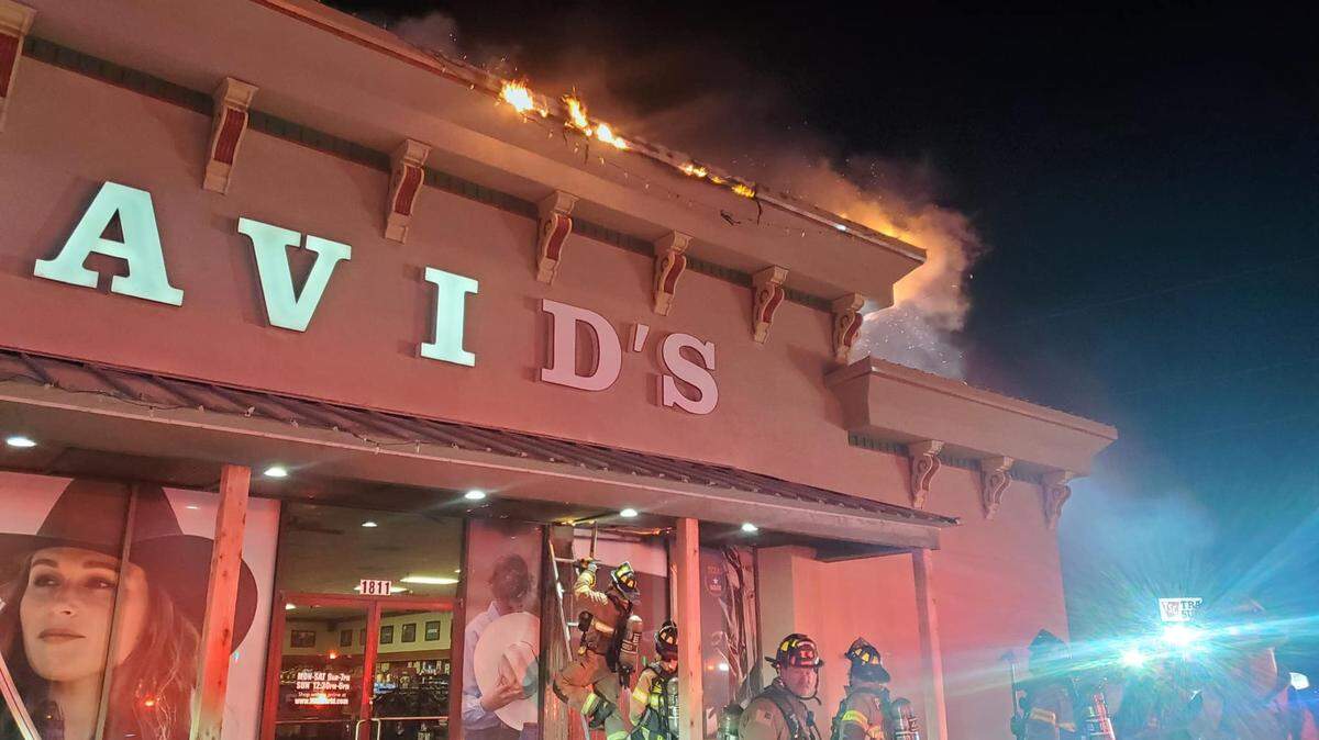 Firefighters respond to a fire at David's Western Store. Flames can be seen on the roof of the building. 