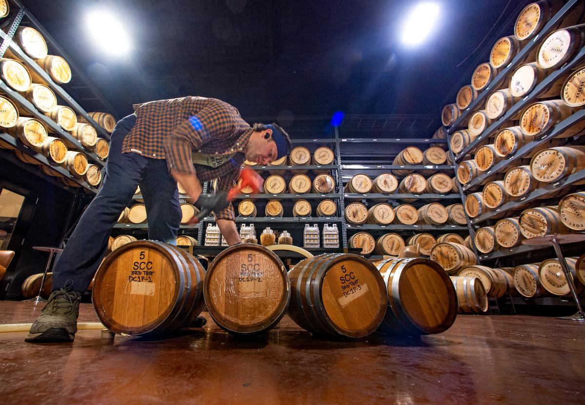 Aaron Hiler, lead distiller at Blackland Distillery, filling up 5 gallon casks for a Devil’s Cask test. The silicone-based coating helps keep whisky from leaking out while still allowing enough air in to maintain the spirit’s flavor. Photo taken Monday, Feb. 6, 2023.