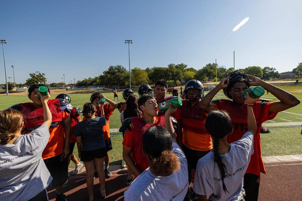 High school football players line up for water after practice at Fort Worth Polytechnic High School in Fort Worth on Thursday, Aug. 10, 2023.
