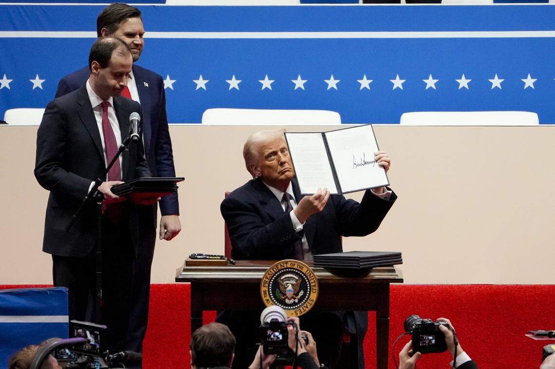 Jan 20, 2025; Washington, DC, USA; President Donald Trump signs a stack of executive orders on stage during the inauguration parade for President Donald Trump at Capital One Arena in Washington D.C., on Monday, Jan. 20, 2025. Mandatory Credit: Sam Greene-Pool via Imagn Images
