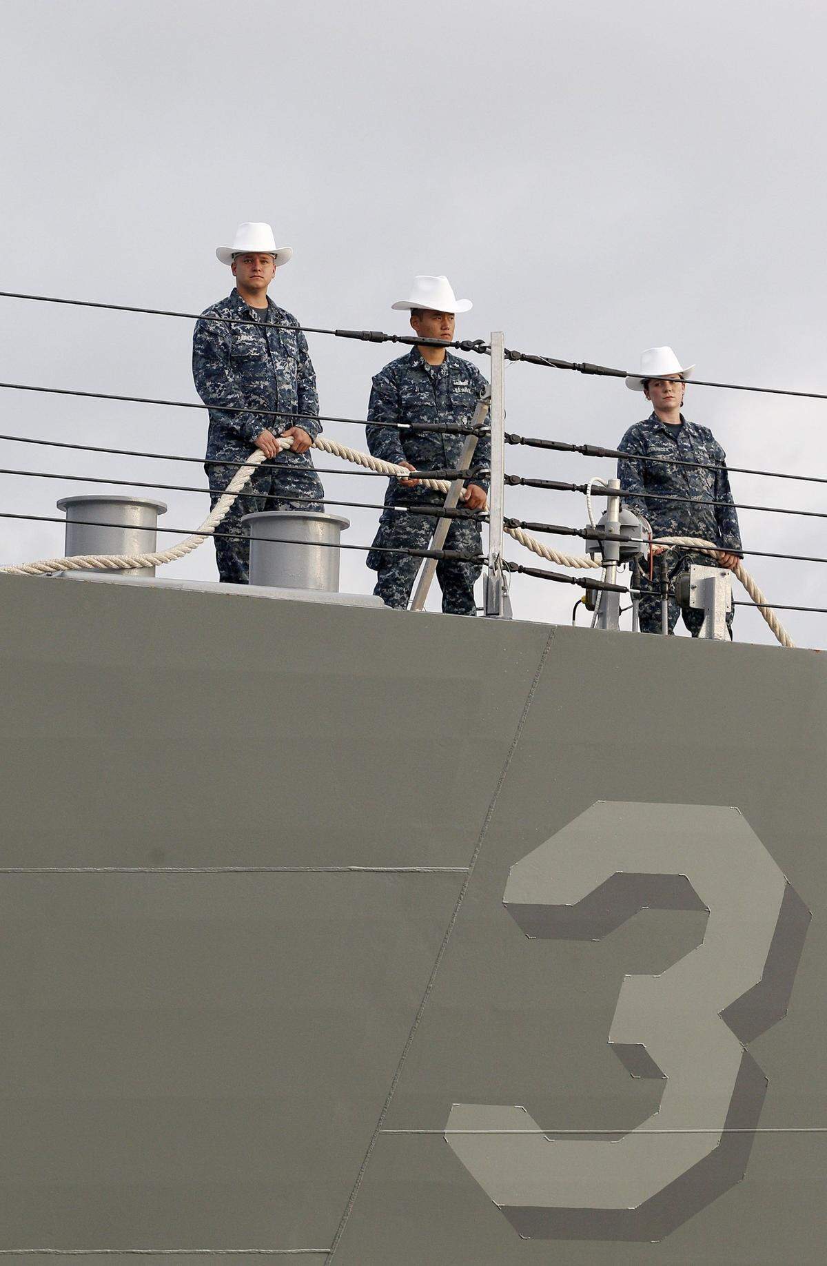 Navy men and women wear cowboy-style hard hats as the USS Forth Worth arrives at the port of Galveston on Monday, Sept. 17, 2012.