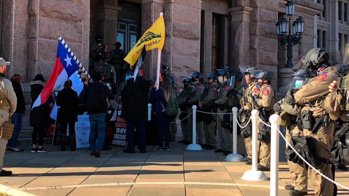 Protesters against COVID-19 vaccines face Texas state troopers wearing riot gear outside the Capitol in Austin on Tuesday.