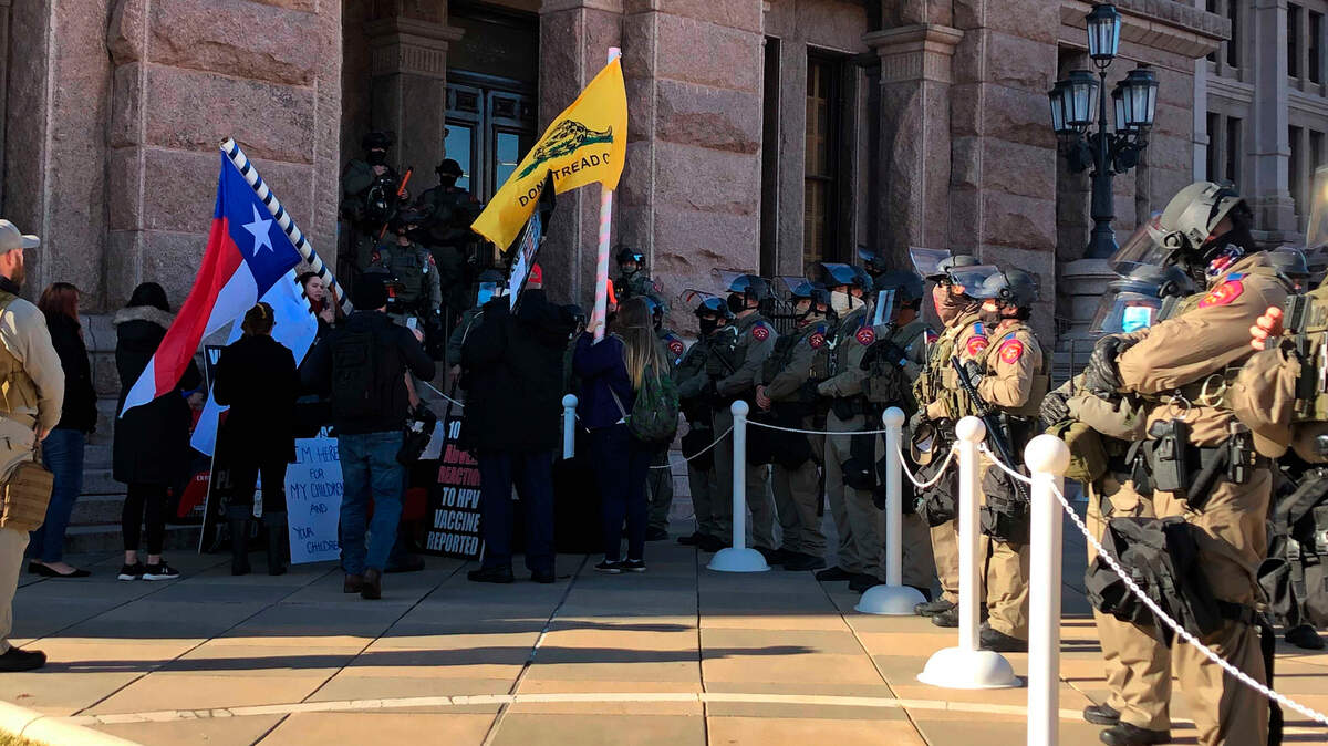 Protesters against COVID-19 vaccines face Texas state troopers wearing riot gear outside the Capitol in Austin on Tuesday.
