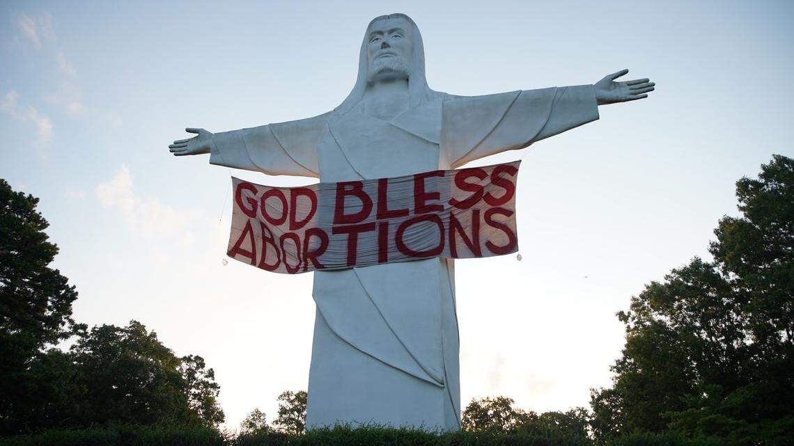 An activist group called Indecline says it hung a “God Bless Abortions” banner overnight Thursday on the Christ of the Ozarks Statue in Arkansas.