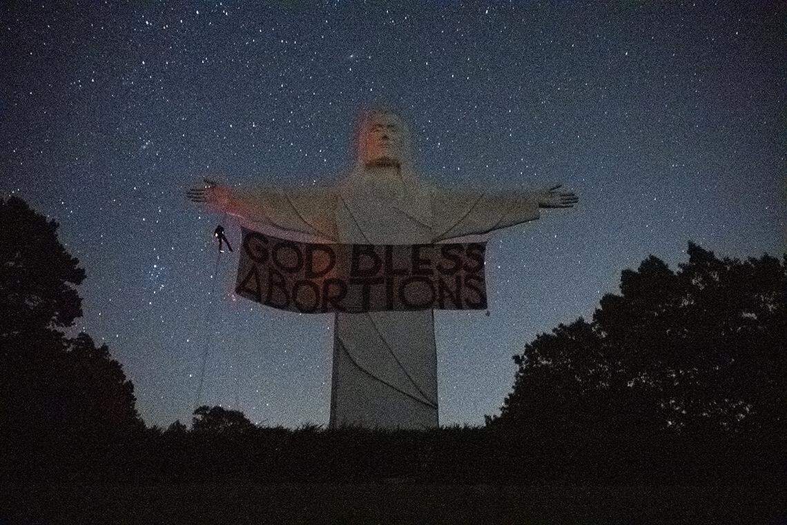 An activist group called Indecline says it hung a “God Bless Abortions” banner overnight Thursday on the Christ of the Ozarks Statue in Arkansas.