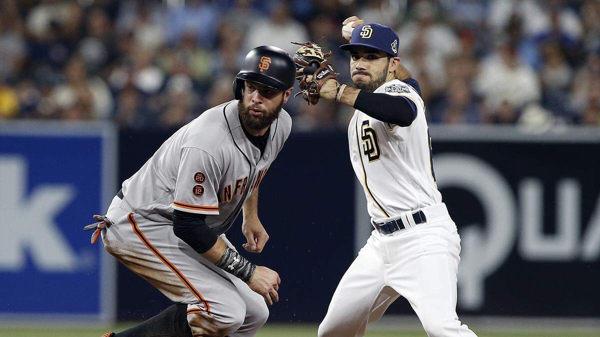 San Francisco Giants’ Brandon Belt, left, looks for the call by an umpire, as San Diego Padres second baseman Carlos Asuaje, right, fails to tag the bag and holds on to the ball on a grounder by Buster Posey, who was safe at first during the fourth inning of a baseball game in San Diego, Saturday, Sept. 24, 2016. (AP Photo/Alex Gallardo)