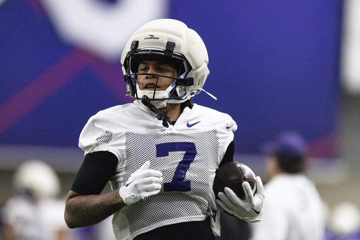 WIde receiver Jordan Dwyers, waist up, running with a ball tucked in his right arm.