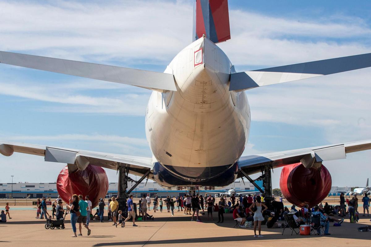 People gather in the shade underneath an airplane at the Fort Worth Alliance Airport in Fort Worth on Saturday, Oct. 22, 2022. The AllianceTexas Aviation Expo presented by Bell offered interactive and educational opportunities face-to-face with dozens of aircrafts spread across the tarmac.