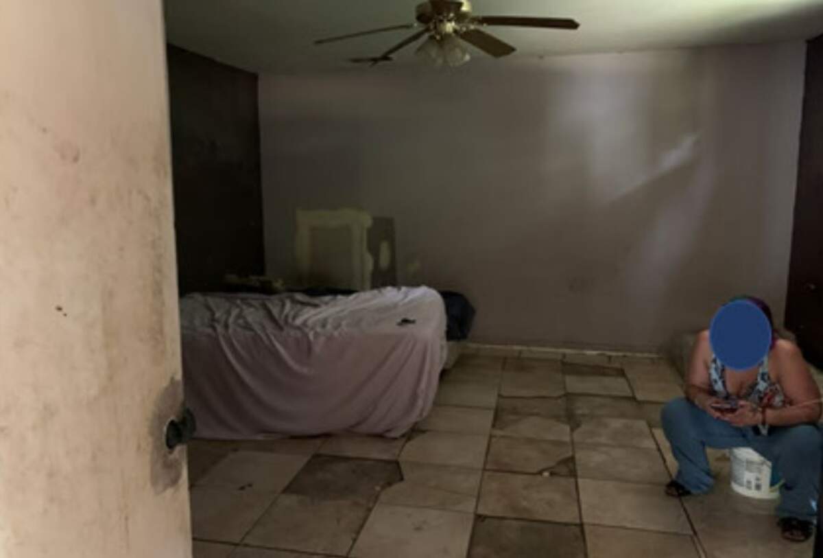 A woman sits atop bucket because she has no place else to sit in this photo of a boarding home from the city of Fort Worth.