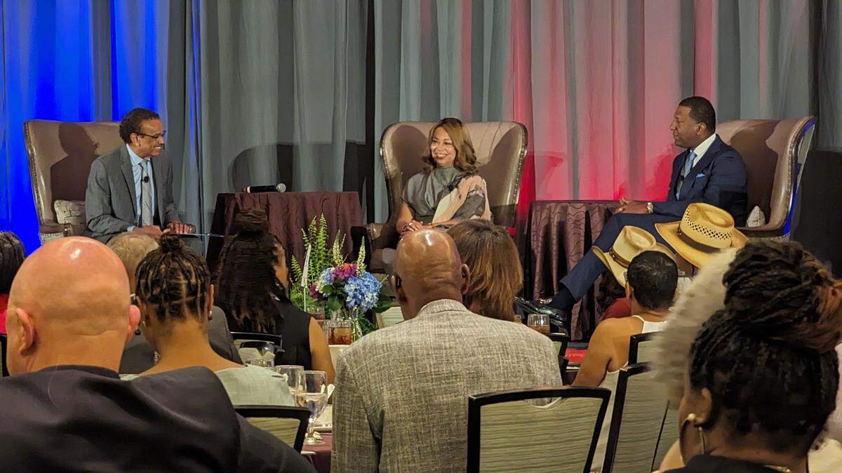 Three people sitting on a stage at a gathering. 
