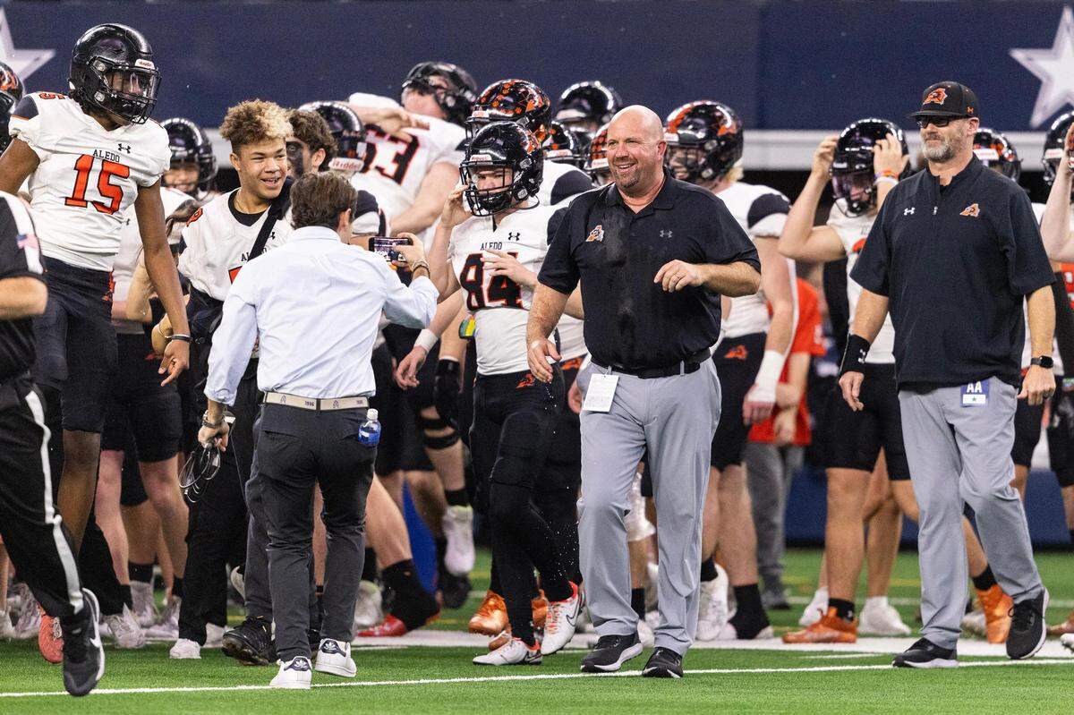 Aledo Head Coach Robby Jones smiles after getting water poured on him after his team won the 5A Division I Football State Championship game against the Comal Smithson Valley Rangers at AT&T Stadium in Arlington on Friday, Dec. 15, 2023. Aledo won 51-8 to capture the programs 12th state title.