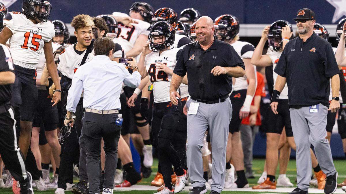 Aledo Head Coach Robby Jones smiles after getting water poured on him after his team won the 5A Division I state championship game against the Comal Smithson Valley Rangers at AT&T Stadium in Arlington on Friday,