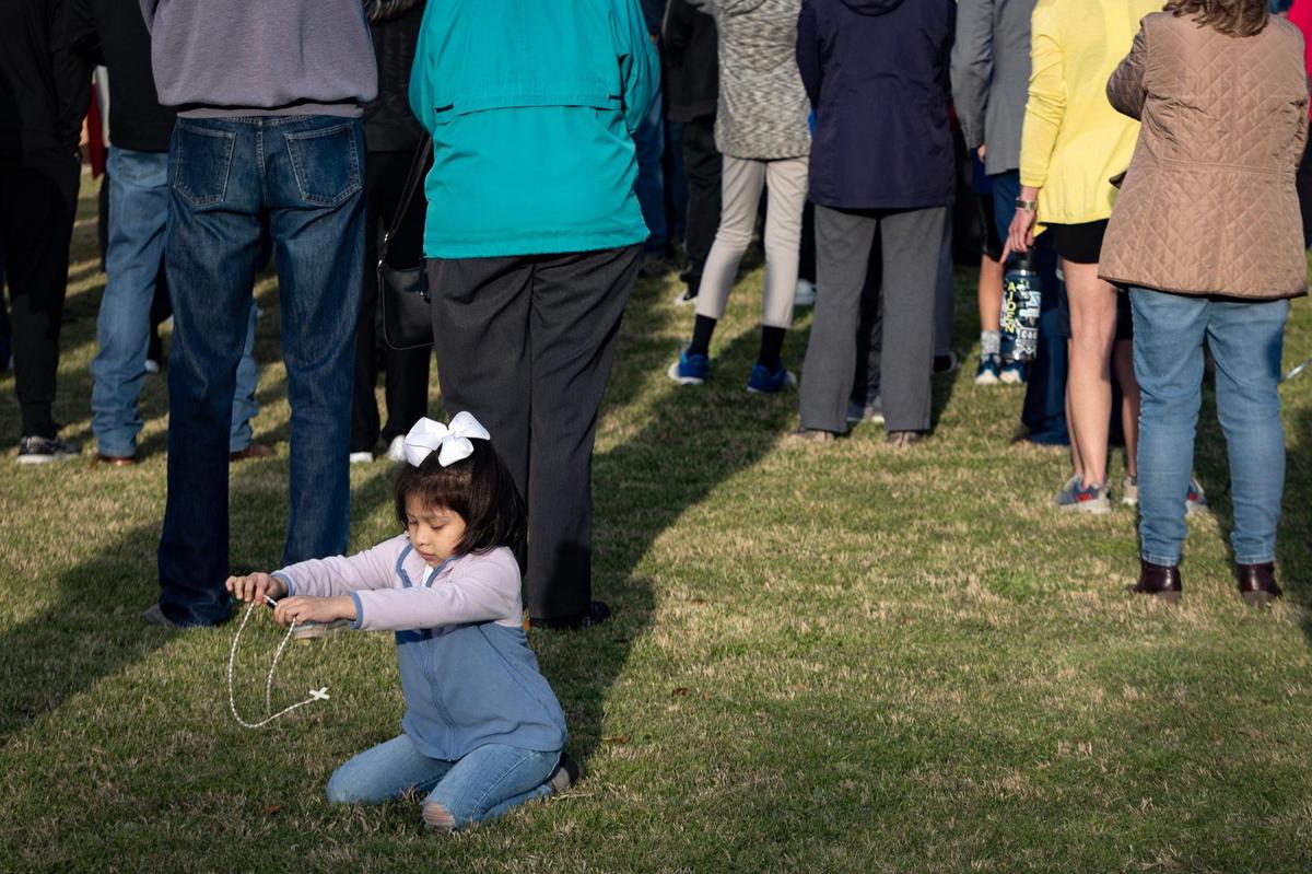 Alexandra Montoya, 4, plays with a rosary while dozens of folks pray during a vigil for Ja’Shawn James Poirier on Tuesday, March 21, 2023, in Arlington. Poirier, 16, was shot by a classmate at Lamar High on Monday, police said.