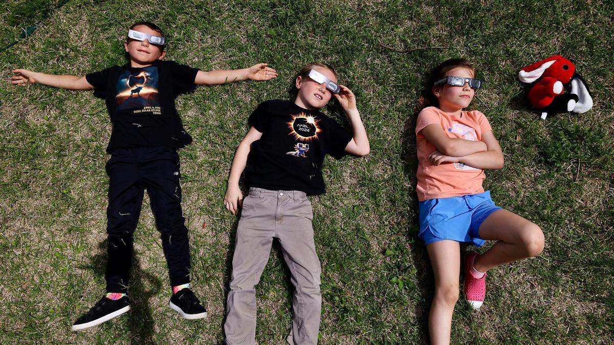 Brothers Nathan, 8 and Dean Dinino, 7 from Washington lay down with Ada June, 8, to watch the solar eclipse outside Hillsboro courthouse on Monday, April 8, 2024.