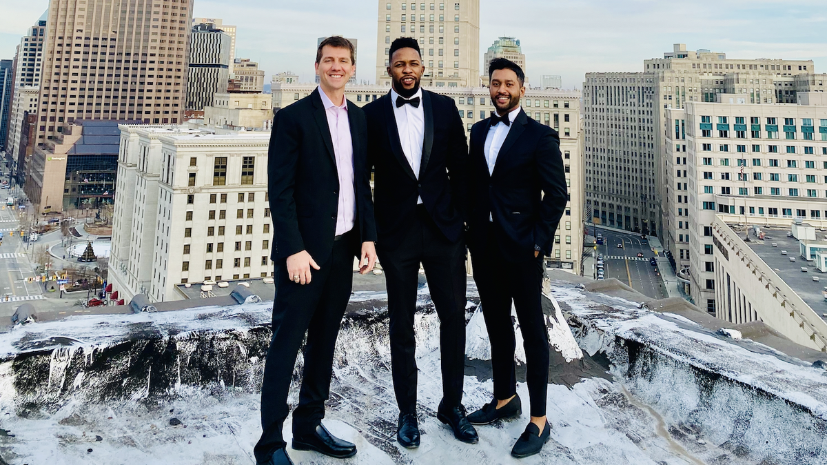 Blueloft investor Kenneth Wolfe and developers Ike Bams and John Williams stand on the roof of a high-rise building, with a city skyline in the background. 