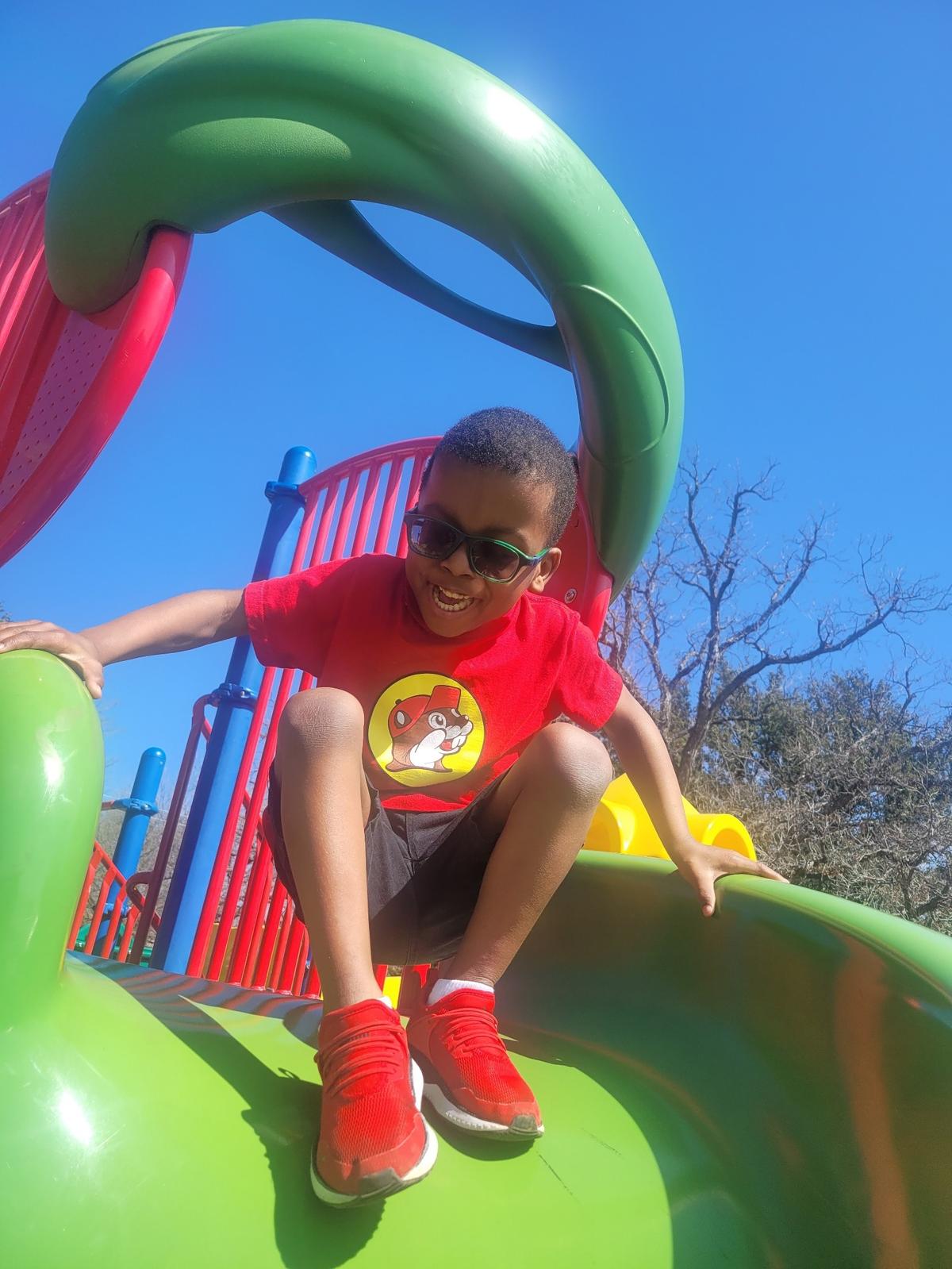 Five-year-old Bryan Dorsey III, of Fort Worth, is pictured going down a slide at a park.