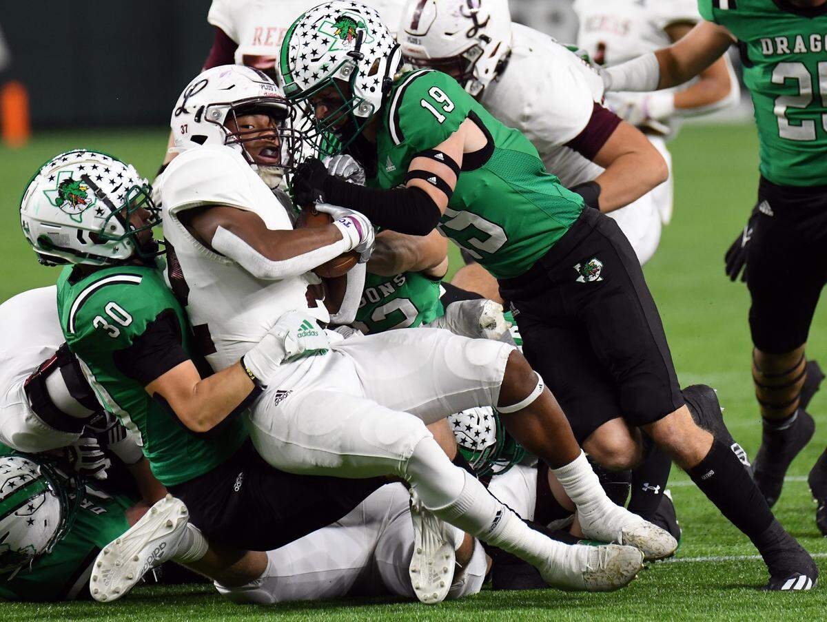 Southlake Carroll’s Nate Gall, left, and Logan Anderson bring down Midland Legacy’s Makhilyn Young for a loss early in the first quarter of their Class 6A Division 1 Area football game Saturday, November 20, 2021 at Globe Life Field in Arlington, Texas. Carroll went on to win 42-7. Special/Bob Haynes