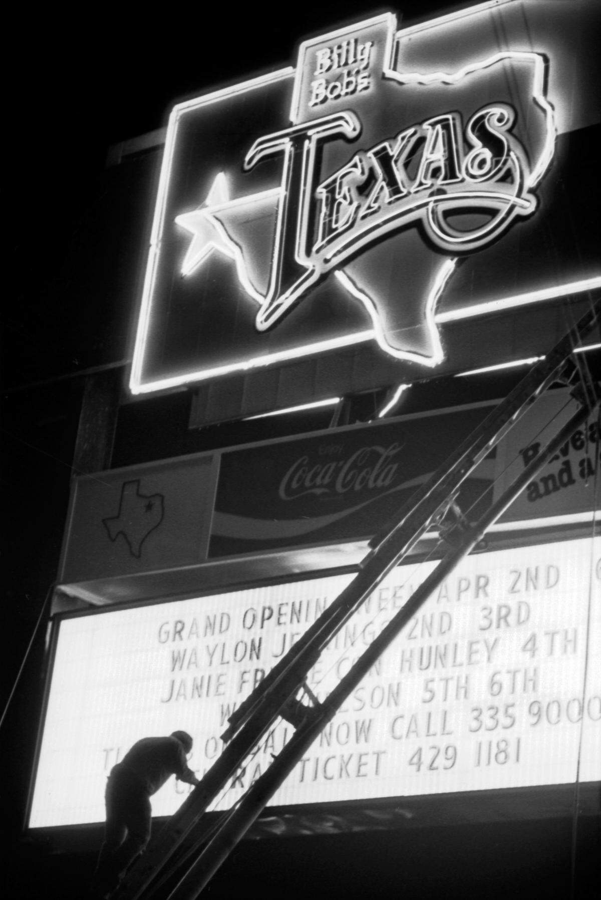 April 2, 1981: Opening night at Billy Bob’s Texas honky-tonk; a workman on a ladder placing letters on the sign.