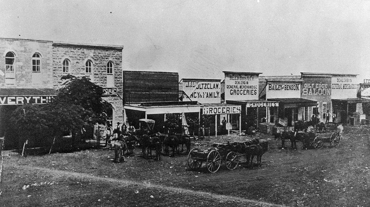 An early street scene in Fort Worth from the 1870s or 1880s showing merchants and saloons that relied on cattle season along Chisholm Trail to bring in business.