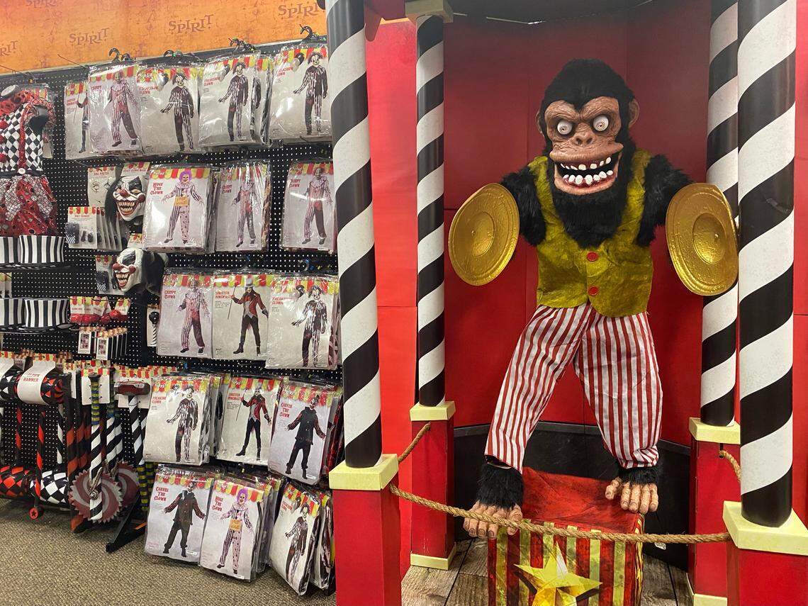 A picture of Spirit Halloween's new Monty animatronic figure with Halloween costumes hanging along the nearby store wall.
