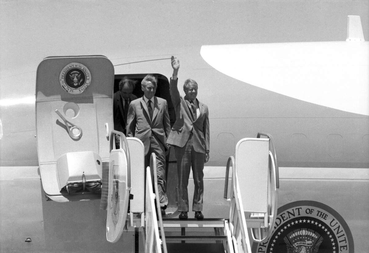 President Carter is seen waving and standing at the stop of the staircase to Air Force One.